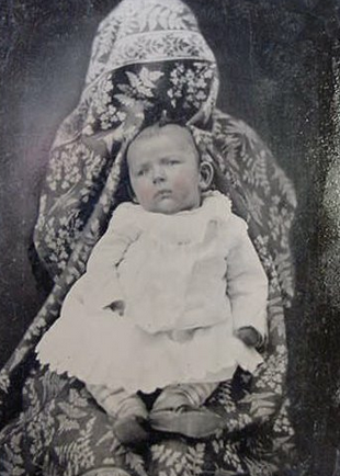Fotografie din epoca victoriană. Ca să nu plângă, copilul era ținut în brațe de mama lui, care era acoperită cu o cuvertură. Fotografie din epoca victoriană. Ca să nu plângă, copilul era ținut în brațe de mama lui, care era acoperită cu o cuvertură.